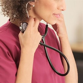 Sköterska som sätter i öronoliverna på sitt 3M Littmann Classic III stetoskop i öronen.